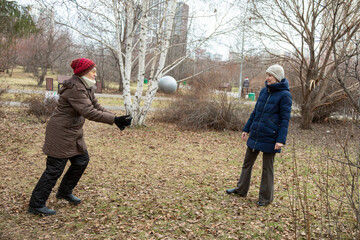 Elderly woman and young woman playing ball in park. Healthy active lifestyle for elderly person. Family leisure time and multigenerational connection.
