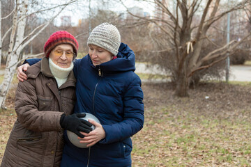 Woman embracing older woman, holding ball, a tender moment between generations, demonstrating care and active lifestyle for seniors.