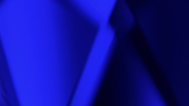 Abstract background with light effects. Dynamic interplay of vibrant blue triangular facets with shifting glows and reflections in motion.