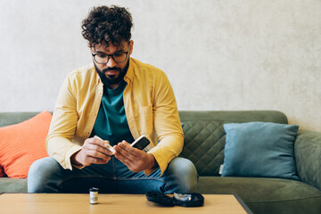 Diabetic man wearing stylish eyeglasses checking blood sugar levels at home sitting on sofa