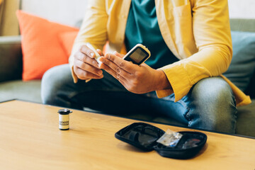 Man checking blood sugar levels with glucometer and lancet sitting at home