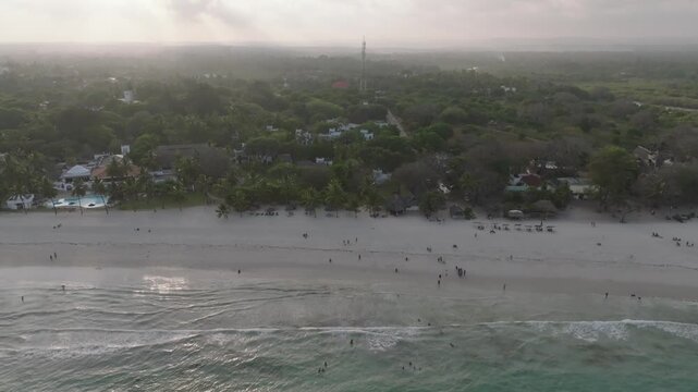 Aerial view of the tranquil beach meeting the turquoise ocean, with a resort nestled amongst lush greenery, Diani, Kwale County, Kenya.