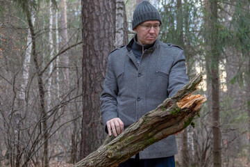 Adult man in an autumn forest collecting deadwood. Male person exploring nature and engaging in outdoor activity for eco-friendly lifestyle.