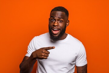 Surprised african american man pointing sideways against orange background