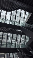 Fototapeta premium Modern architectural staircase with glass railings and large windows offers a stunning view of the urban cityscape, showcasing contemporary design and geometric patterns.