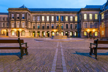 View of the cobblestone ground reflecting the soft glow of lights illuminating the historic Binnenhof palace at twilight, Binnenhof, the Hague, Netherlands.