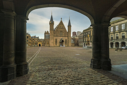 View of the majestic Binnenhof castle with its gothic spires piercing the sky, framed by stone archways in The Hague, The Hague, Netherlands.