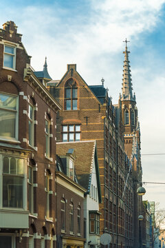 View of striking brick buildings stand shoulder-to-shoulder under a vibrant blue sky, the spire of a church piercing the skyline, The Hague, South Holland, Netherlands.