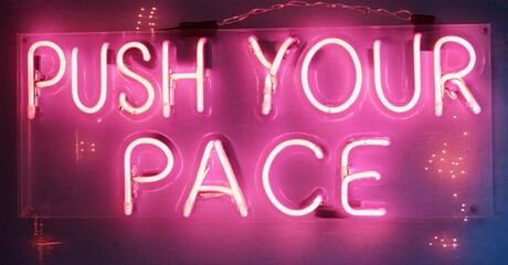 Fototapeta premium Bright pink neon sign displays motivational phrase push your pace. Dark background emphasizes glowing text. Simple, direct message.