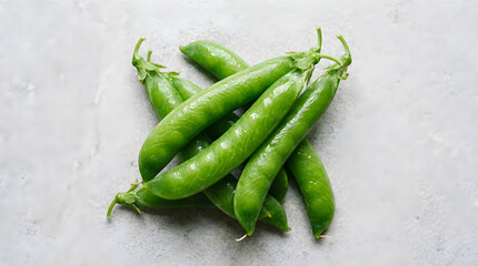  fresh green peas arranged in a crisscross pattern on a smooth, light gray marble surface. 