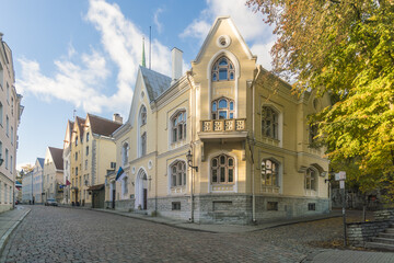 View of the ornate architecture of a corner building stands bathed in warm sunlight against a backdrop of cobblestone streets, Tallinn, Harju County, Estonia.
