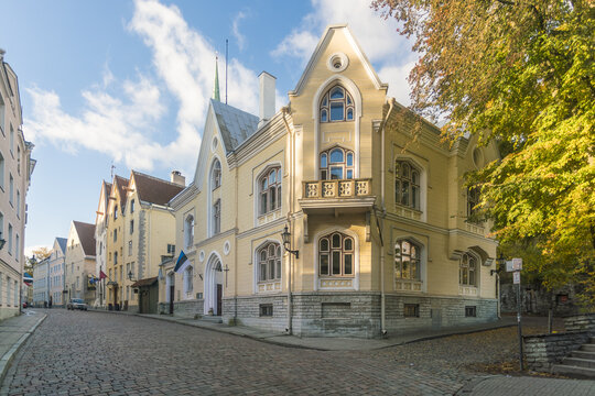 View of the ornate architecture of a corner building stands bathed in warm sunlight against a backdrop of cobblestone streets, Tallinn, Harju County, Estonia.
