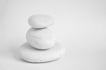 Modern balance minimalism. Pyramid of white stones on a white background, still life of natural pebbles.