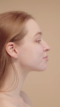 Young woman doing her morning skincare routine, applying sunscreen face cream and makeup base, preparing skin for makeup, part of daily beauty regimen. Vertical video