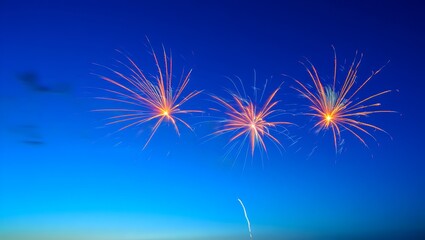 Three bright orange fireworks burst against a deep twilight blue sky, with a single trail below.