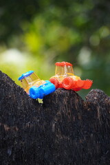 Colorful Plastic Water Tap Attached to a Tree Trunk in a Lush Green Environment.