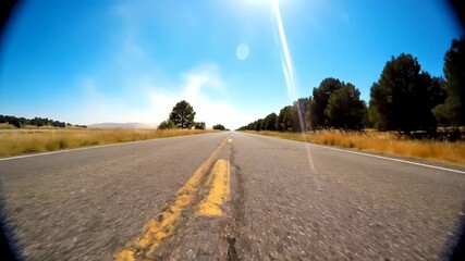 Empty asphalt road with trees and grass on the side under a clear blue sky