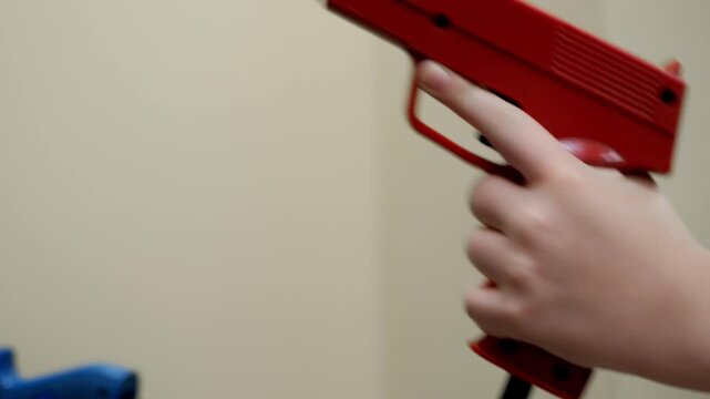 A player reaches for a red arcade light gun, lifts it from the cabinet holder, and aims toward a shooter game screen, showing classic arcade interaction and controller handling.