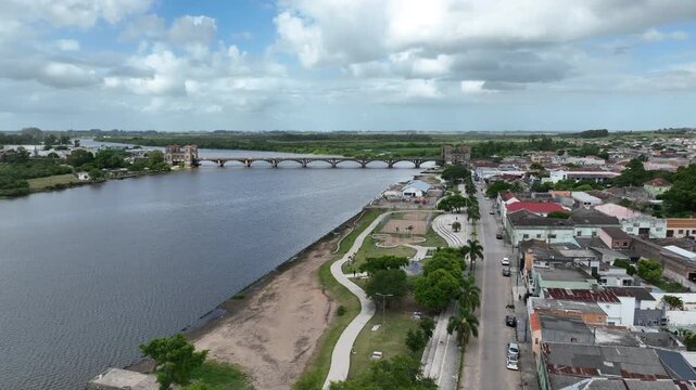 Wide cinematic drone orbit over Jaguarao riverfront. Establishing shot revealing the historic Maua International Bridge and the border of Brazil and Uruguay. Professional 4K master quality.