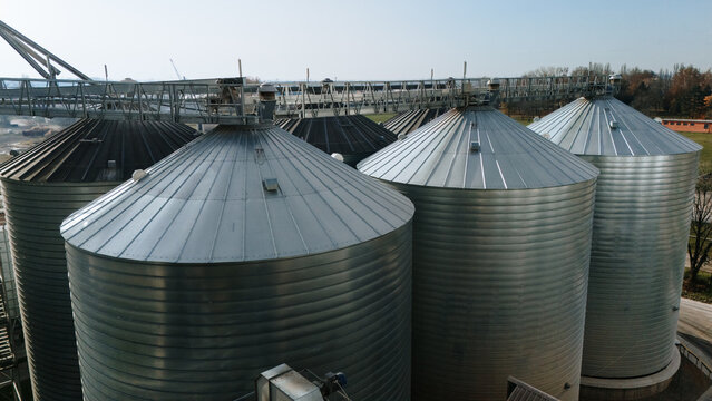 Aerial view of gleaming metal silos stand tall against the horizon, their conical roofs reflecting the sunlight, Sremska Mitrovica, Vojvodina, Serbia.