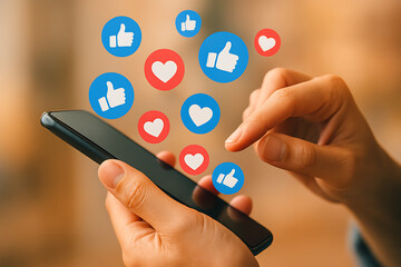 Finger tapping smartphone screen with floating social media like and heart icons representing modern communication and connectivity