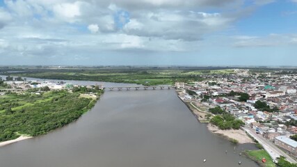 Symmetrical drone view from the middle of the river between Brazil and Uruguay. Drone ascends while tilting down to show both border cities and the international bridge. Professional 4K master.