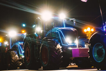 Modern agricultural tractors brightly illuminated with headlights and glowing blue neon-like lights at night. Dynamic shot of powerful farm machinery in a festive parade, showcasing innovation and cel