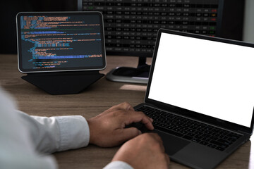 Close up of hands typing on a laptop at an office desk with a blank screen mockup and copy space, programming code and data analysis setup in the background.