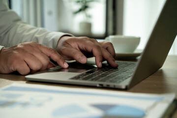 Close up laptop typing hands at office desk laptop work, business working on computer with report documents and data analysis concept
