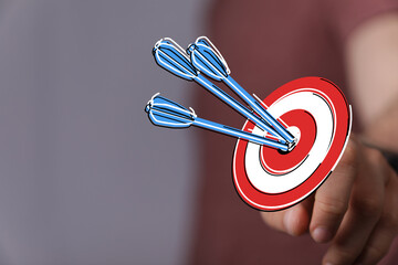 Hand holding a bullseye with darts. Concept of success, achieving goals, and strategy. Business and motivation illustration. Aiming and focusing