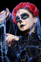 Halloween beauty portrait of woman. Female face with Santa Muerte makeup and entangled in old web.