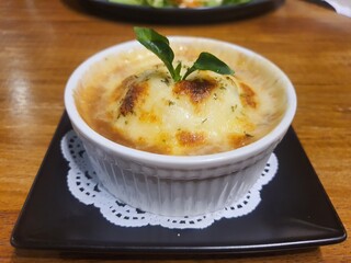 Baked mashed potatoes with cheese in a white cup.