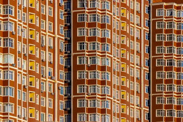 View of the towering terracotta-colored building rises majestically, its symmetrical facade punctuated by rows of windows catching the light, Aktau, Mangystau Region, Kazakhstan.