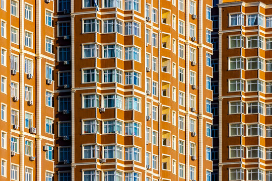View of towering orange buildings with symmetrical rows of windows reflecting the sky, creating a vibrant urban landscape, Aktau, Mangystau Region, Kazakhstan.