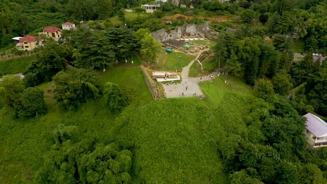 Aerial video shows ancient petra fortress ruins surrounded by lush green hills and trees near batumi georgia with smooth drone movement cinematic travel style natural daylight atmosphere calm mood