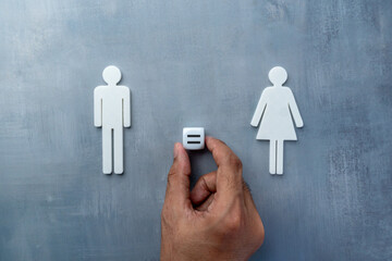 A hand places an equal sign between male and female symbols. Gender equality, equal rights, fairness, and social justice concepts.