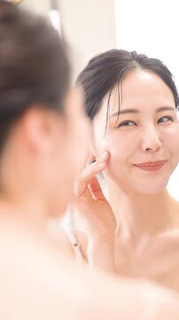 鏡を見るケアする女性　保湿とスキンケアの縦動画