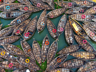 Aerial view of countless wooden boats clustered together with colorful lifebuoys, creating a vibrant tapestry on the water's surface, Dhaka, Dhaka Division, Bangladesh.