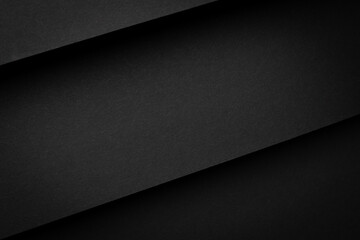 Black paper sheets layered on a flat surface create a simple design