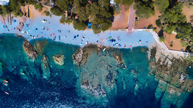 Aerial view of the vibrant coastline where the azure sea meets the sandy beach near rocky outcrops, framed by lush greenery, St Rapha&Atilde;&laquo;l, France.