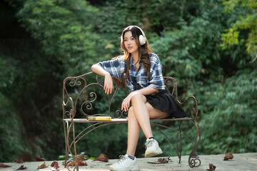 A beautiful Asian teenage girl is happily listening to music with headphones.