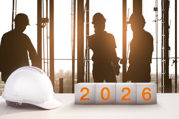 Happy New Year 2026 Real Estate and Construction Industry. White Helmet and a numbered concrete cube on the desk of an engineer or construction worker. welcome new year party and change new business