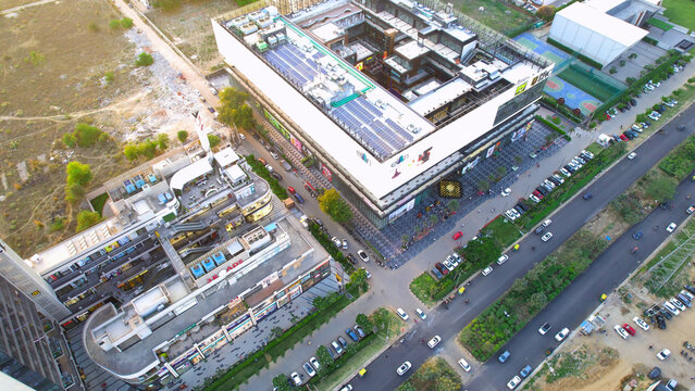 aerial drone shot looking down at Elan Reach shopping malls on side of busy street with cars, vehicles showing the development of commercial real estate in Gurgaon