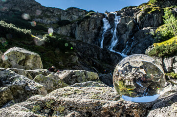 a glass ball against the backdrop of a waterfall
