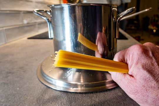 Stockholm, Sweden A cook holds a handfull of spaghetti pasta in his hand on a kitchen counter.