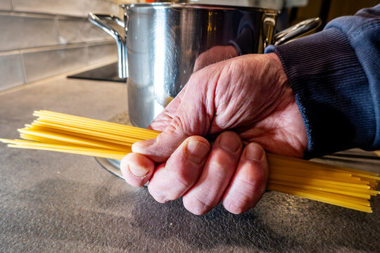 Stockholm, Sweden A cook holds a handfull of spaghetti pasta in his hand on a kitchen counter.