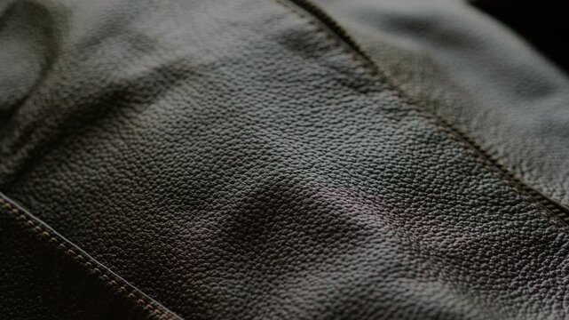 Close-up macro shot of dark leather duffle bag featuring prominent zipper running diagonally through the frame. Detailed texture of grainy leather. Durability and craftsmanship