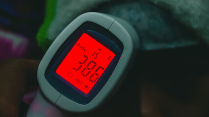 Close-up of a digital thermometer showing a temperature reading in a dimly lit environment