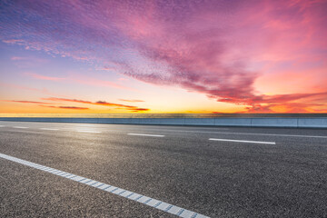 Empty asphalt highway road and coastline with colorful sky clouds landscape at sunset