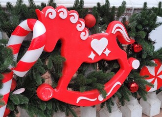 The facades of buildings and streets of the city are decorated with green Christmas tree branches, balls and garlands